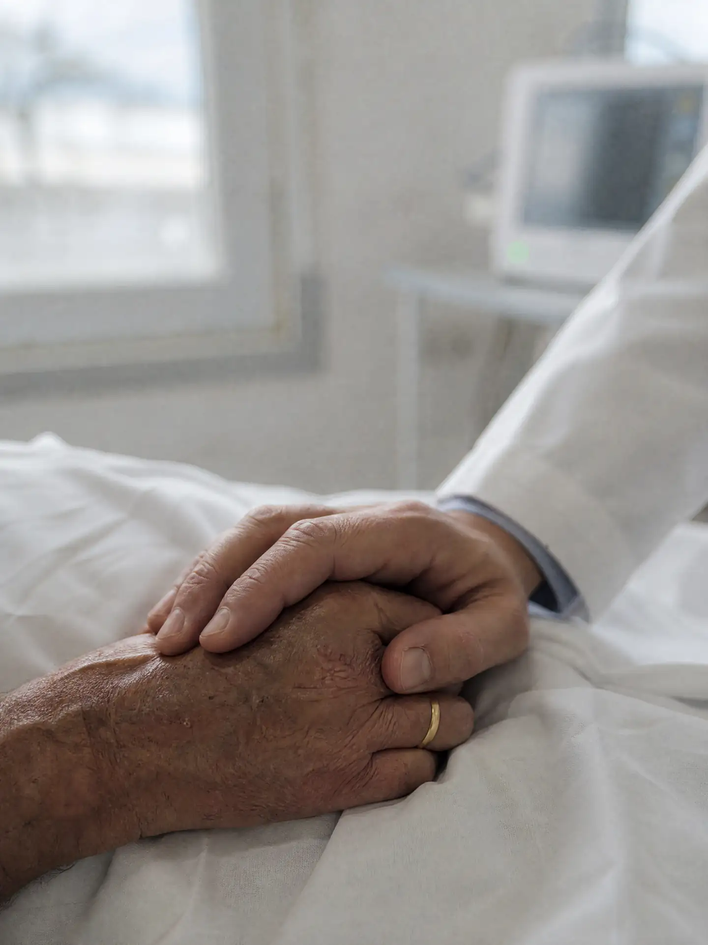Mão de um médico sobre a mão de um paciente idoso